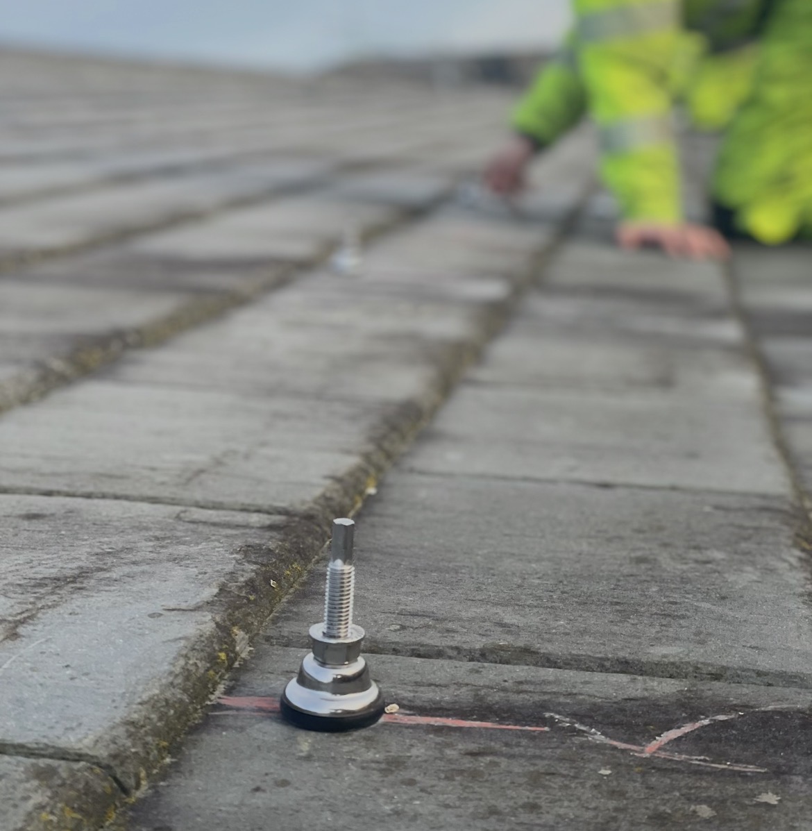 Close-up of a single SolVe Mount installed on Cambrian interlocking slate, installer visible behind